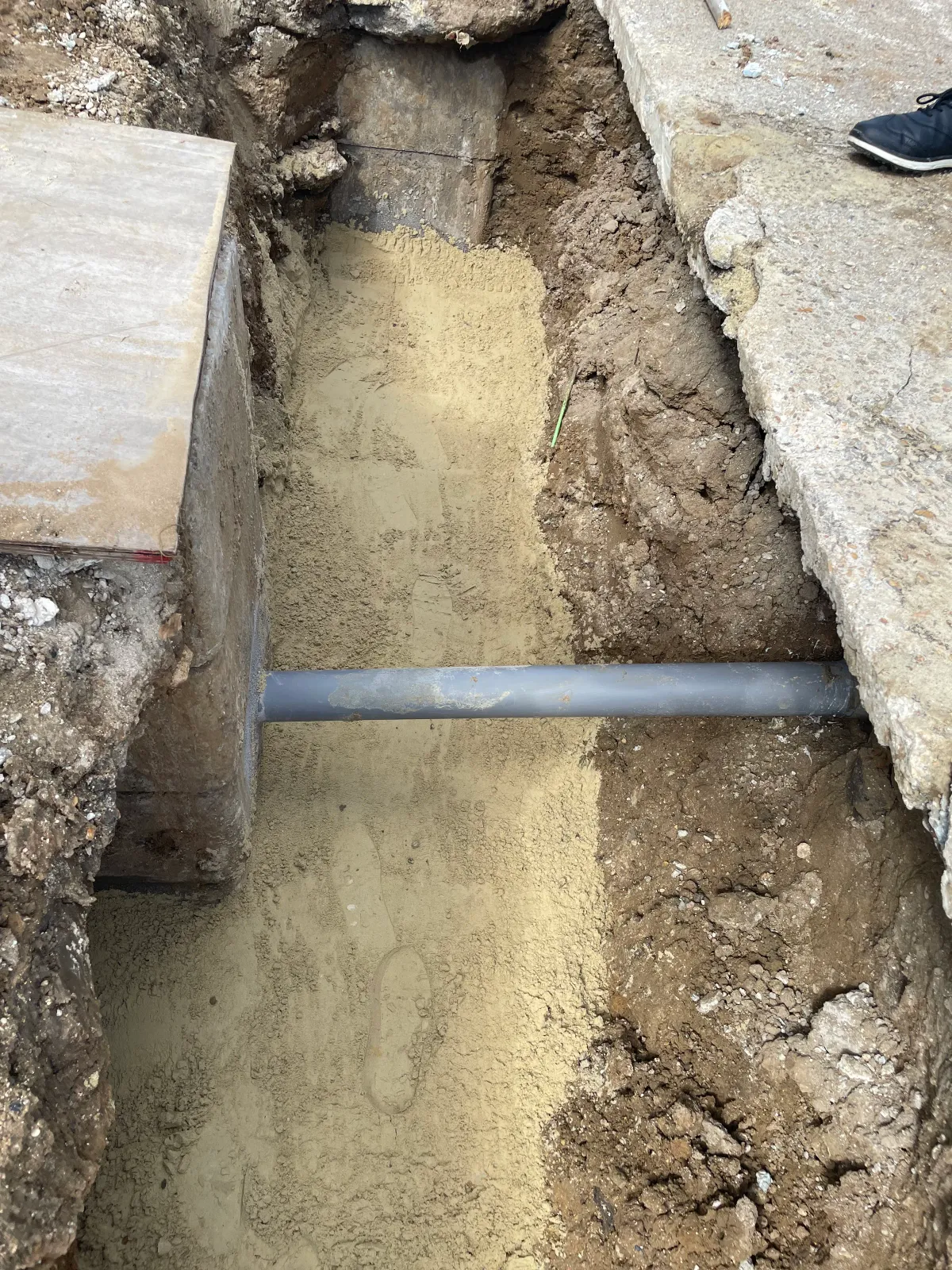 Tranchée de réseaux divers le long d'un mur sur un chantier VRD